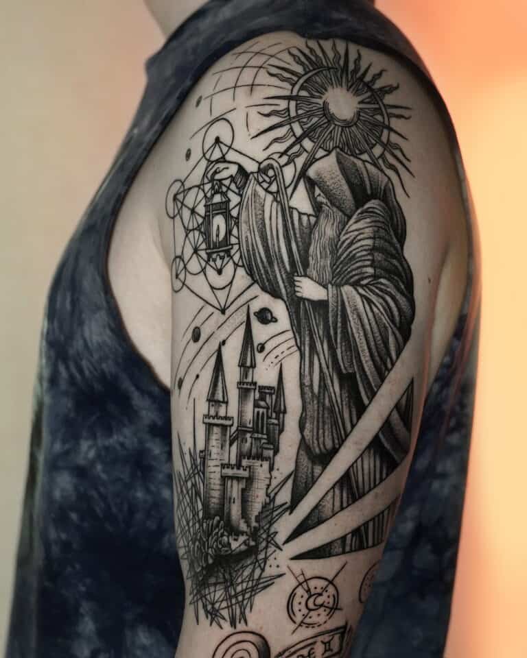 Na górnej części ramienia znajduje się szczegółowy czarno-szary tatuaż uchwycony jako DSC00054 przez 7sinstattoo.live. Wzór przedstawia postać w szacie trzymającą latarnię, stojącą nad zamkiem z trzema wieżami. Skomplikowane tło obejmuje geometryczne kształty, słońce z promieniami i różne abstrakcyjne elementy. Osoba ma na sobie ciemną koszulę bez rękawów. Aby zobaczyć podobne arcydzieła, odwiedź nasze wiodące studio tatuażu w Poznaniu, Seven Sins Tattoo.