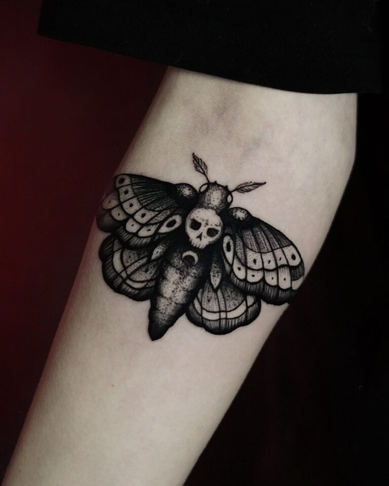 Tatuaż przedstawiający misternie wykonaną trupią główkę ćmy z czaszką na tułowiu, stworzony przez renomowane studio Seven Sins Tattoo w Poznaniu, jest umieszczony na wewnętrznej stronie przedramienia człowieka. Misternie cieniowane czarne i szare skrzydła są również umieszczone obok półksiężyca u podstawy ciała ćmy. To arcydzieło jest wymienione jako produkt DSC00294 z 7sinstattoo.live.
