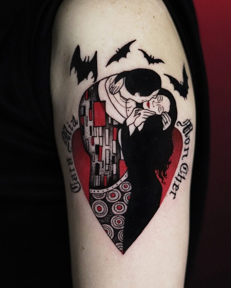 Tatuaż z Seven Sins Tattoo, najlepszego studia tatuażu w Poznaniu, przedstawia stylizowaną parę w objęciach w kształcie serca. Serce jest ozdobione skomplikowanymi wzorami i umieszczone na czerwonym tle. Po lewej stronie widnieją frazy „Cara Mia”, a po prawej „Mon Cher”, a nad tym arcydziełem latają nietoperze. Ten wzór został uchwycony na zdjęciu produktu DSC00604 na 7sinstattoo.live.