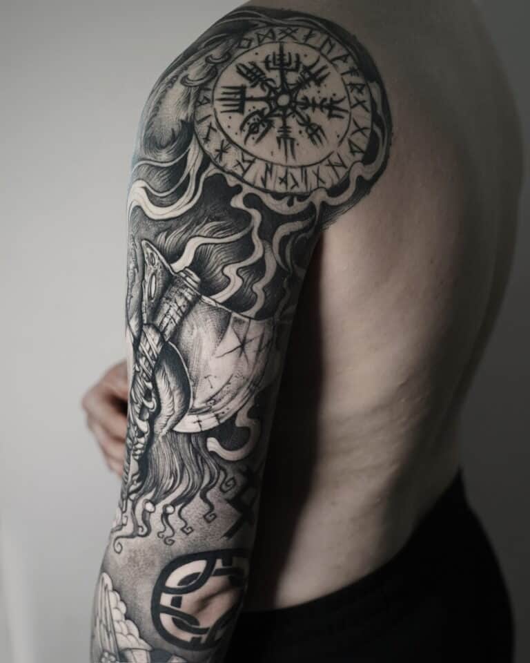 7sinstattoo.live Górna część ramienia i bark osoby prezentujące misterny czarno-szary tatuaż ozdobiony symbolami nordyckimi, podkreślony Vegvisir (runiczny kompas) na ramieniu i różnymi innymi wzorami pokrywającymi całą długość ramienia. Ten element został wykonany w studio tatuażu Poznań, znanym jako najlepsze studio tatuażu Poznań. Proste, jasne tło dodaje idealnego kontrastu, aby podkreślić tę grafikę uchwyconą w DSC03395. Najlepsze studio tatuażu Seven Sins Tattoo