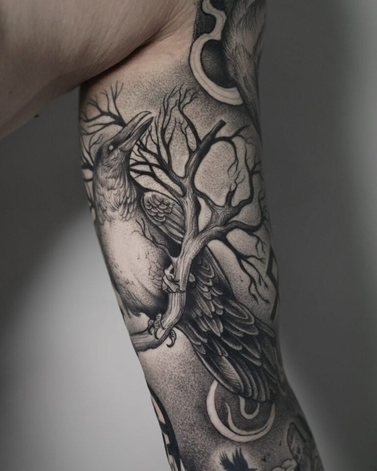 7sinstattoo.live Szczegółowy czarno-szary tatuaż, oznaczony jako DSC03442 i stworzony w Najlepszym Studio Tatuażu Poznań, przedstawia kruka siedzącego na sękatej gałęzi drzewa na ramieniu człowieka. Wzór charakteryzuje się misternym cieniowaniem i cienkimi liniami, dzięki czemu zarówno ptak, jak i gałąź wyglądają realistycznie. Najlepsze studio tatuażu Seven Sins Tattoo