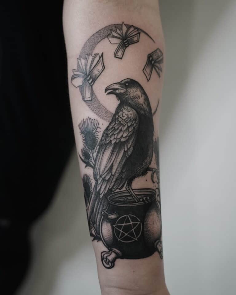 7sinstattoo.live Szczegółowy czarno-szary tatuaż (DSC08830ррр) na ramieniu przedstawia wronę siedzącą na kotle ozdobionym symbolem pentagramu. Nad wroną znajduje się zakrzywiony układ unoszących się książek, wszystko na tle roślin przypominających osty, które podkreślają mistyczny motyw. Ten misterny element został umiejętnie wykonany w Studio Tatuażu Poznań. Najlepsze studio tatuażu Seven Sins Tattoo