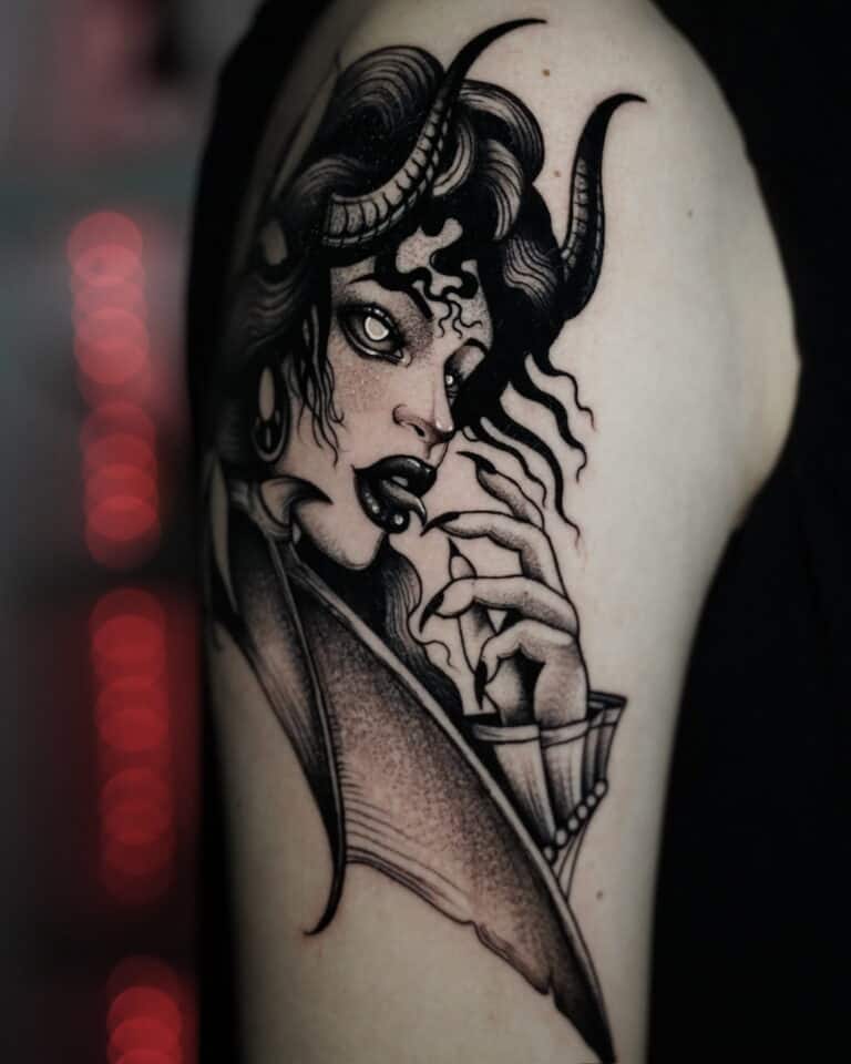 7sinstattoo.live Czarno-szary tatuaż o nazwie DSC09961 przedstawia kobietę o rogowych rysach twarzy, kręconych włosach i intensywnym wyrazie twarzy. Trzyma rękę blisko twarzy, pokazując widoczne kły i spiczaste paznokcie. Tło jest rozmyte czerwonymi i czarnymi tonami. Stworzony w studio tatuażu Poznań, ten uderzający element zdobi górną część ramienia. Najlepsze studio tatuażu Seven Sins Tattoo