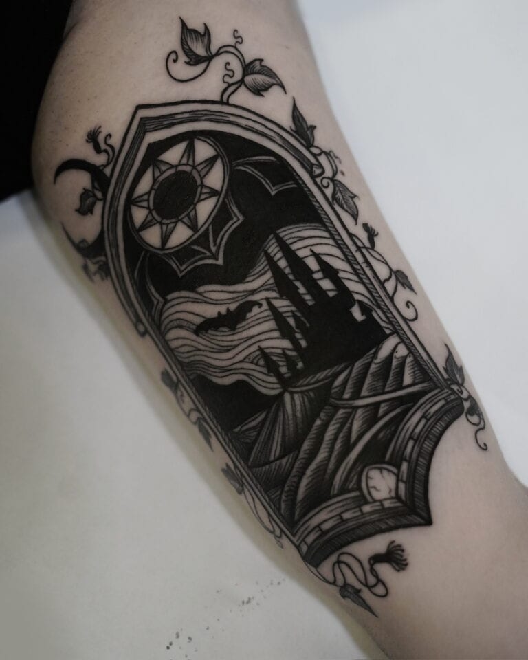 7sinstattoo.live Oszałamiający czarny tatuaż na skórze, oznaczony jako DSC09965, przedstawia gotyckie okno łukowe oplecione misternymi pnączami. W oknie ciemny zamek znajduje się na tle księżycowego nieba pełnego nietoperzy i chmur. Nad łukiem symbol słońca zapewnia uderzający kontrast z nocną sceną poniżej — prawdziwe arcydzieło tatuażysty Poznań w studio tatuażu Poznań. Najlepsze studio tatuażu Seven Sins Tattoo