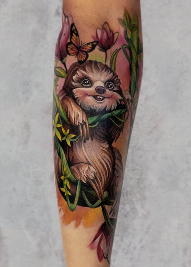7sinstattoo.live Szczegółowy i kolorowy tatuaż uśmiechniętego leniwca czepiającego się zielonych winorośli z różowymi i fioletowymi kwiatami, któremu towarzyszy motyl nad głową, umieszczony na przedramieniu na jasnoszarym tle, pięknie wykonany przez utalentowanych artystów ze studia tatuaży Poznań. Dzieło jest oznaczone jako produkt b1. Najlepsze studio tatuażu Seven Sins Tattoo