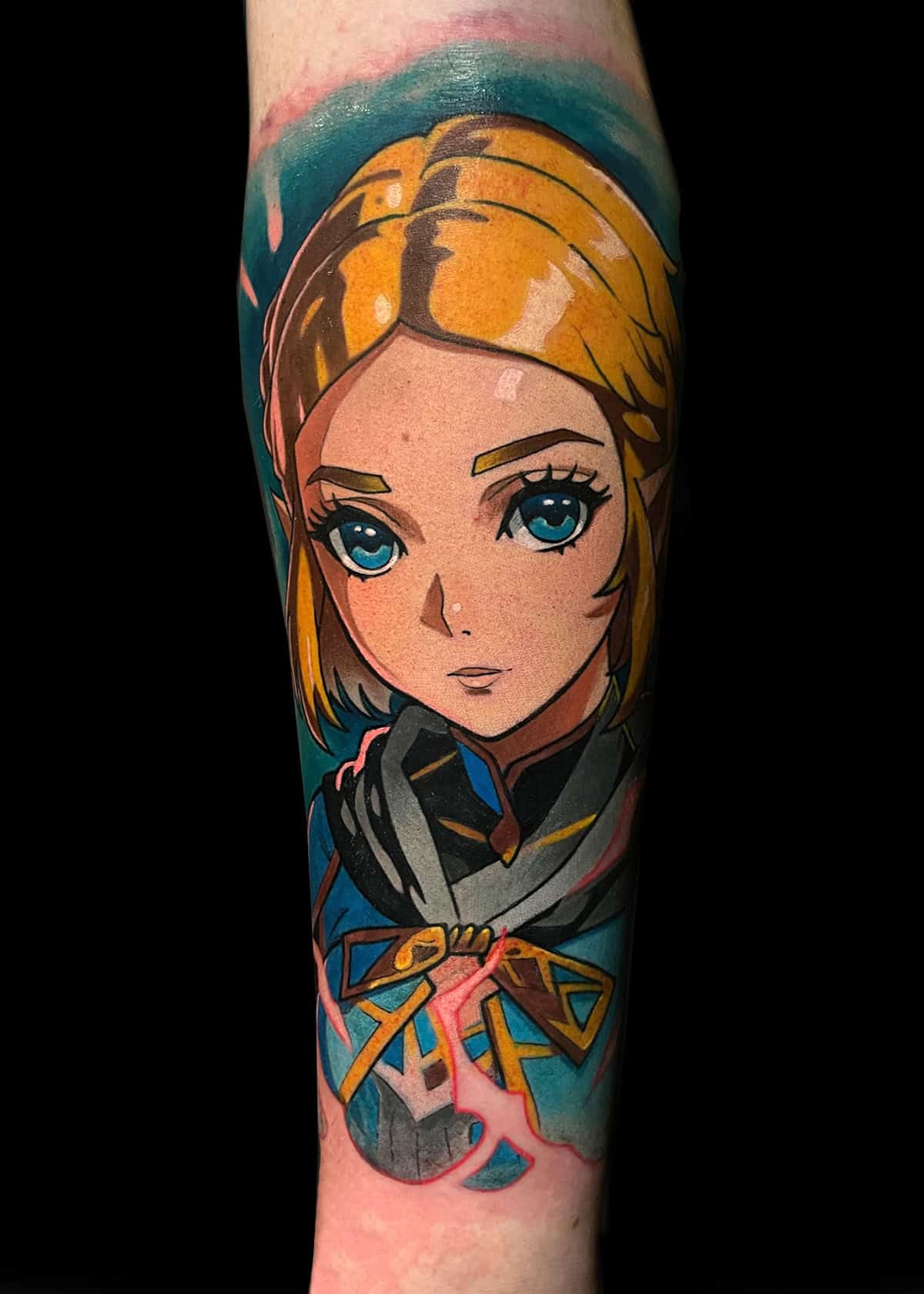 Żywy tatuaż postaci z anime o blond włosach, niebieskich oczach i poważnym wyrazie twarzy. Postać ma na sobie ciemny strój z żółtą kokardą na szyi. Tatuaż charakteryzuje się odważnymi, kolorowymi liniami i cieniowaniem, a tło przechodzi z turkusowego w czarne.
