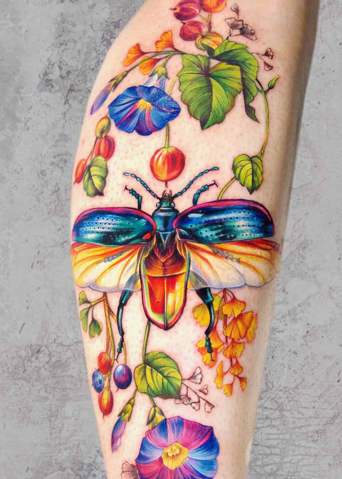 A Żywy tatuaż na przedramieniu, wykonany w Seven Sins Tattoo Poznań, przedstawia kolorowego chrząszcza z opalizującymi skrzydłami. Chrząszcz jest różnorodnymi jasnymi kwiatami i zielonymi składnikami, stanowiącymi żywy i szczegółowy wzór na jasnej rzeczywistości.