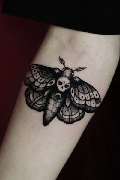 Tatuaż przedstawiający misternie wykonaną trupią główkę ćmy z czaszką na tułowiu, stworzony przez renomowane studio Seven Sins Tattoo w Poznaniu, jest umieszczony na wewnętrznej stronie przedramienia człowieka. Misternie cieniowane czarne i szare skrzydła są również umieszczone obok półksiężyca u podstawy ciała ćmy. To arcydzieło jest wymienione jako produkt DSC00294 z 7sinstattoo.live.