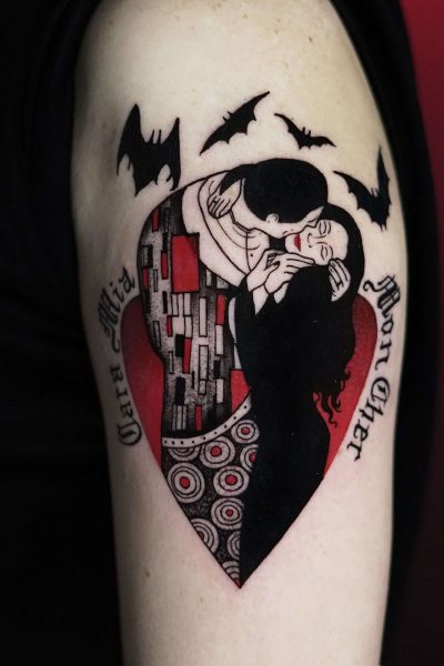 Tatuaż z Seven Sins Tattoo, najlepszego studia tatuażu w Poznaniu, przedstawia stylizowaną parę w objęciach w kształcie serca. Serce jest ozdobione skomplikowanymi wzorami i umieszczone na czerwonym tle. Po lewej stronie widnieją frazy „Cara Mia”, a po prawej „Mon Cher”, a nad tym arcydziełem latają nietoperze. Ten wzór został uchwycony na zdjęciu produktu DSC00604 na 7sinstattoo.live.