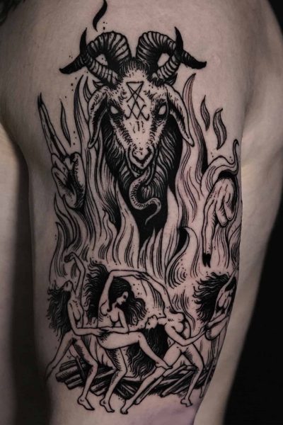Szczegółowy czarny tatuaż na górnej części ramienia, stworzony przez artystę z najlepszego studia tatuażu w Poznaniu, Seven Sins Tattoo, przedstawia postać z głową kozy z rogami i okultystycznymi symbolami nad nią. Zatytułowany „DSC01117”, ten projekt przedstawia trzy nagie postacie w rozpaczy lub agonii, otoczone płomieniami i poskręcanymi gałęziami, prezentujące skomplikowane elementy ruchu i wysoki kontrast.