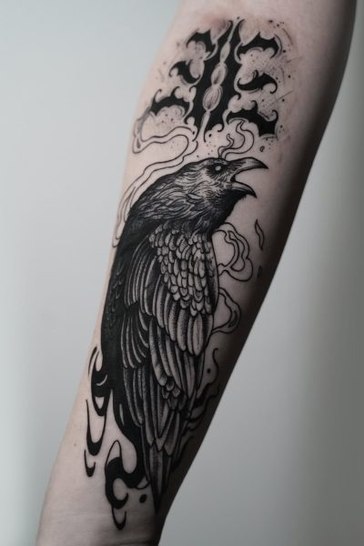 7sinstattoo.live Szczegółowy czarno-szary tatuaż kruka jest przedstawiony na przedramieniu człowieka. Ciało kruka i pióra są misternie narysowane, z wirującymi abstrakcyjnymi wzorami i stylizowanym wzorem otaczającym je dla uzyskania artystycznego efektu. To arcydzieło zostało wykonane w najlepszym studiu tatuażu w Poznaniu, znanym z wyjątkowego kunsztu, i jest prezentowane jako produkt DSC03273. Najlepsze studio tatuażu Seven Sins Tattoo