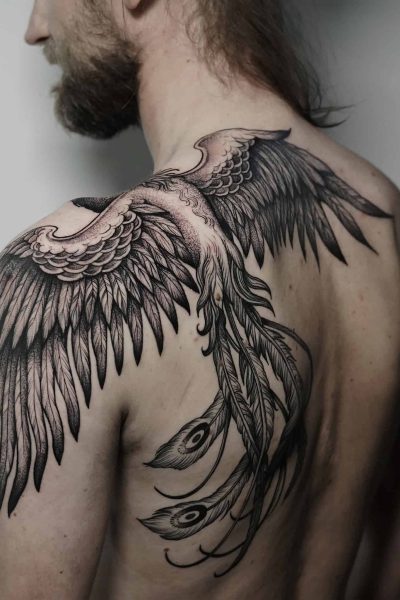 7sinstattoo.live Osoba z długimi włosami pokazuje plecy, odsłaniając skomplikowany tatuaż dużych, szczegółowych skrzydeł ptaka, które rozciągają się od jej ramion. Tatuaż, nazwany DSC05558 i wykonany w najlepszym studio tatuażu Poznań, zawiera również pióra z wzorami przypominającymi oczy, przypominającymi pióra pawia. Najlepsze studio tatuażu Seven Sins Tattoo