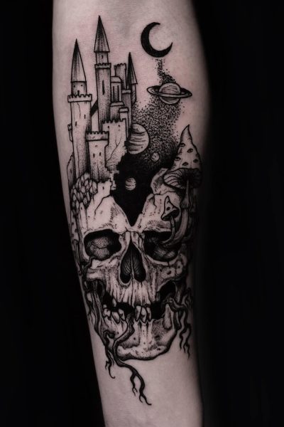 7sinstattoo.live Produkt DSC09344 przedstawia czarno-biały wzór tatuażu przedstawiający czaszkę z korzeniami i grzybami u podstawy, przechodzącą w średniowieczny zamek z wysokimi iglicami. Elementy niebieskie, w tym półksiężyc i planety, są przedstawione nad zamkiem na jednolitym czarnym tle. Ta skomplikowana grafika została stworzona przez artystę ze Studio Tatuażu Poznań. Najlepsze studio tatuażu Seven Sins Tattoo