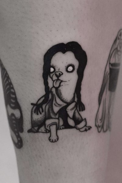 7sinstattoo.live Tatuaż z DSC09960, najlepszego studia tatuażu Poznań, przedstawia niezwykłe stworzenie z długimi czarnymi włosami, białymi oczami bez źrenic i wystającym językiem. Ta postać o dużej głowie i małym ciele siedzi ze zgiętymi kolanami i uniesionymi ramionami. Wykonany czarnym tuszem, wyróżnia się uderzająco na skórze osoby. Najlepsze studio tatuażu Seven Sins Tattoo