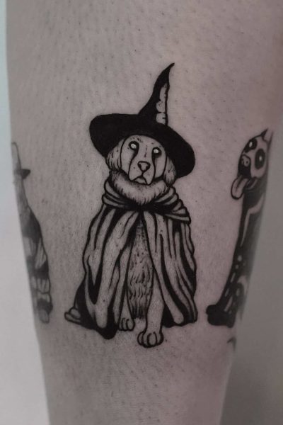 7sinstattoo.live Przyjrzyj się urzekającemu czarno-białemu tatuażowi psa ubranego w strój czarodzieja. Pies jest przedstawiony w spiczastym kapeluszu i płaszczu, klasycznych elementach stroju czarodzieja. Ten wyjątkowy element, zatytułowany DSC09978, został fachowo wykonany na skórze przez jednego z najbardziej utalentowanych artystów ze Studia Tatuażu w Poznaniu. Najlepsze studio tatuażu Seven Sins Tattoo